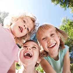 three kids smiling outside
