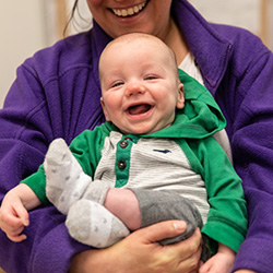 Baby boy sitting on teachers lap laughing