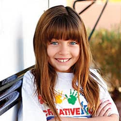 young girl leaning against school bus