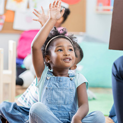 little girl raising hand in class